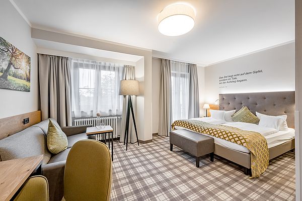 Hotelzimmer mit Sitzbank, Sitzecke mit Sofa und Leselampe und Schreibtisch